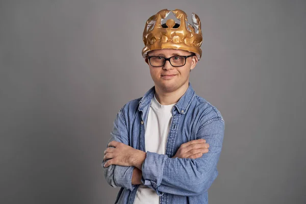 灰色の背景に王冠を身に着けているダウン症候群を持つ男の肖像 — ストック写真