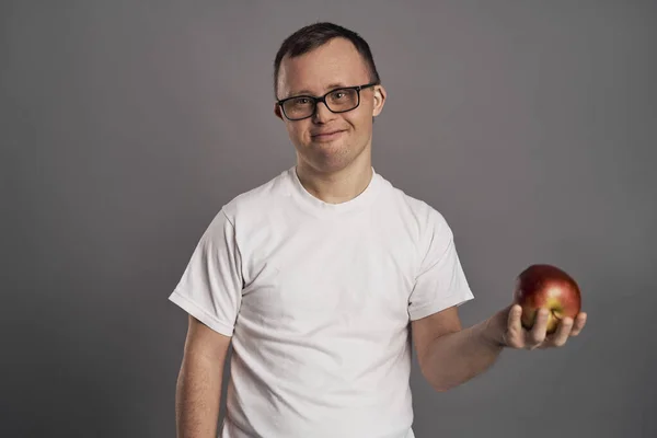 Muž Downovým Syndromem Drží Jablečné Ruce Šedém Pozadí — Stock fotografie