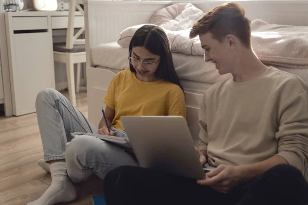 两个高加索青少年一边坐在地板上一边玩乐 一边从书本和笔记本电脑中学习 — 图库照片