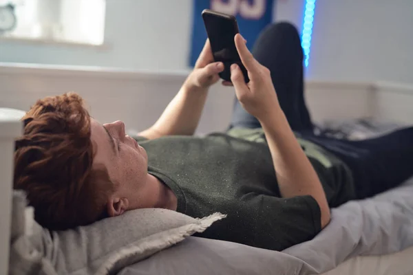 Blank Tiener Jongen Browsen Telefoon Terwijl Liggend Bed Zijn Rug — Stockfoto