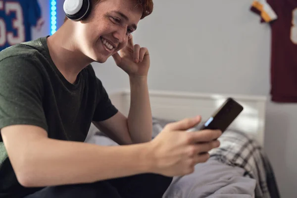 Kaukasischer Teenager Surft Mit Einem Lächeln Telefon Und Trägt Kopfhörer — Stockfoto