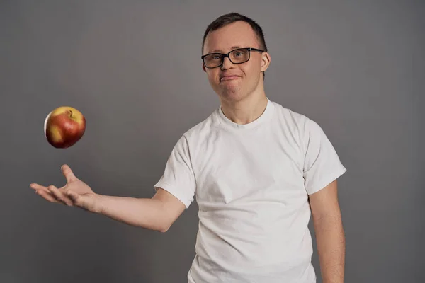 Muž Downovým Syndromem Zvrací Jablko Rukou Šedém Pozadí — Stock fotografie