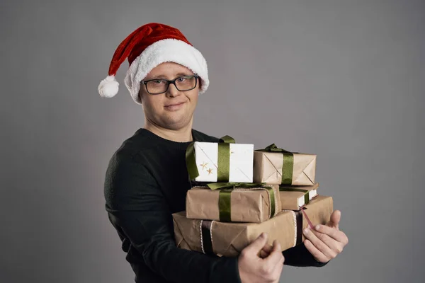 患有唐氏综合症的男人手里拿着一堆圣诞礼物 — 图库照片