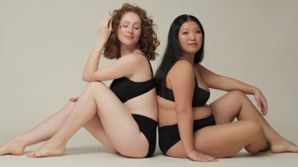 Zwei Frauen Unterwäsche Sitzen Rücken Rücken Auf Dem Boden Studio — Stockvideo