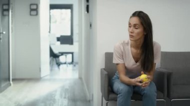 Stresli beyaz kadın klinik bekleme odasında oturmuş stres topu sıkarken. 8K 'da kırmızı helyum kamerayla çekildi..