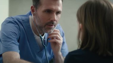 Kafkasyalı pratisyen doktor steteskoplu bir kızı muayene ediyor. 8K 'da kırmızı helyum kamerayla çekildi.. 