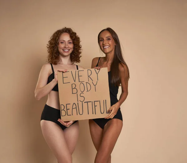 两名身穿内裤的高加索女人站在工作室里赤身裸体 举着横幅 — 图库照片
