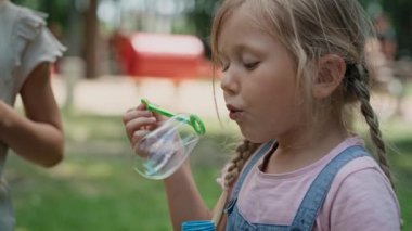 Beyaz kız parkta sabun köpüğü üflüyor. 8K 'da kırmızı helyum kamerayla çekildi..  