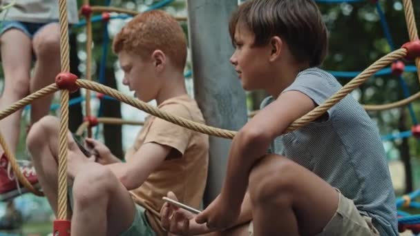 Группа Мальчиков Использующих Мобильный Телефон Детской Площадке Съемка Красной Гелиевой — стоковое видео