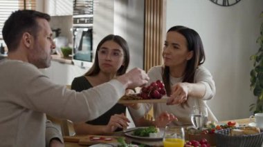 Üç kişilik beyaz bir aile kahvaltı yemeklerini paylaşıyor. 8K 'da kırmızı helyum kamerayla çekildi.. 