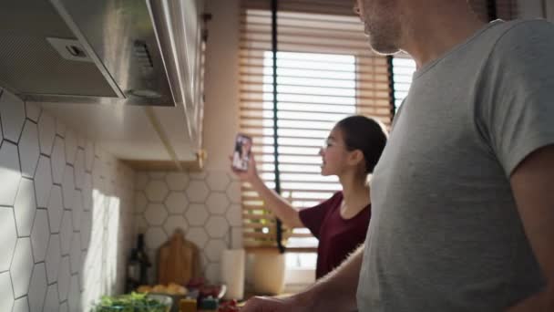 白人のティーンエイジャーの女の子と彼女の父は料理中に母親とビデオ通話を持っています 8Kでレッドヘリウムカメラで撮影 — ストック動画