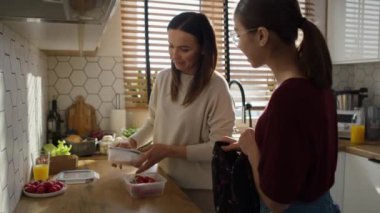 Beyaz bir anne kızına okula beslenme çantası veriyor. 8K 'da kırmızı helyum kamerayla çekildi.. 