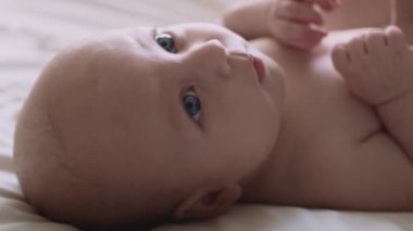 Yeni doğmuş bir bebeğin yatakta yatıp gözlerini kaçırması. 8K 'da kırmızı helyum kamerayla çekildi.. 