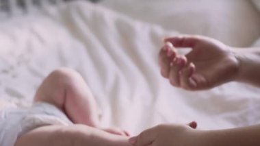 Anne bebeğin ayaklarına nemlendirici merhem sürüyor. 8K 'da kırmızı helyum kamerayla çekildi..    