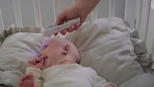 泣いている赤ん坊に温度を測定する認識できない女性 8Kでレッドヘリウムカメラで撮影 — ストック動画