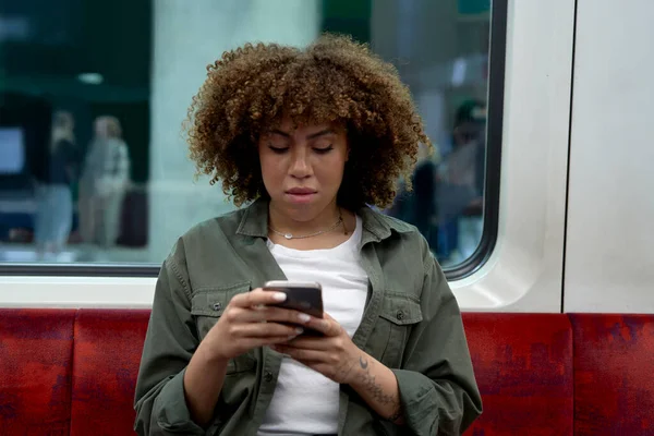 Młoda Afro Kobieta Podróżująca Metrem Przeglądająca Telefon Komórkowy — Zdjęcie stockowe