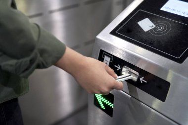 Tanımlanamayan bir kadın yeraltındaki turnikeye bilet koyuyor.