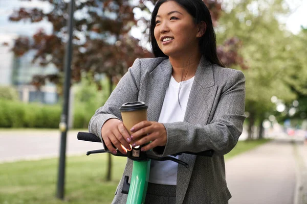 Chińska Kobieta Stojąca Skuterze Elektrycznym Stroju Biznesowym Trzymająca Filiżankę Kawy — Zdjęcie stockowe