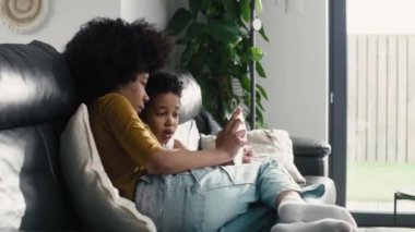 Oturma odasında iki çocuğun dijital tableti karıştırdığı geniş açı. 8K 'da kırmızı helyum kamerayla çekildi..  