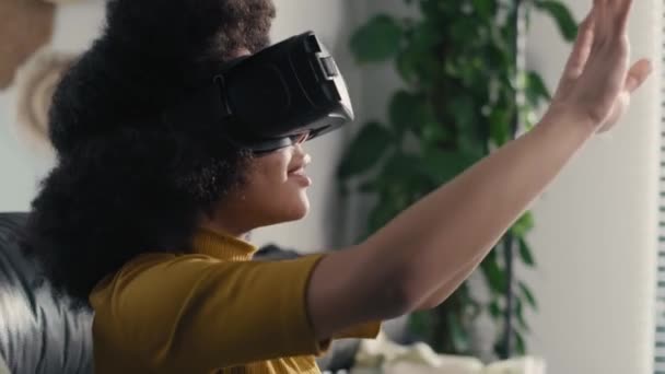 リビングルームでビデオゲームをプレイするために仮想現実シミュレータを身に着けている10代の少女 8Kでレッドヘリウムカメラで撮影 — ストック動画