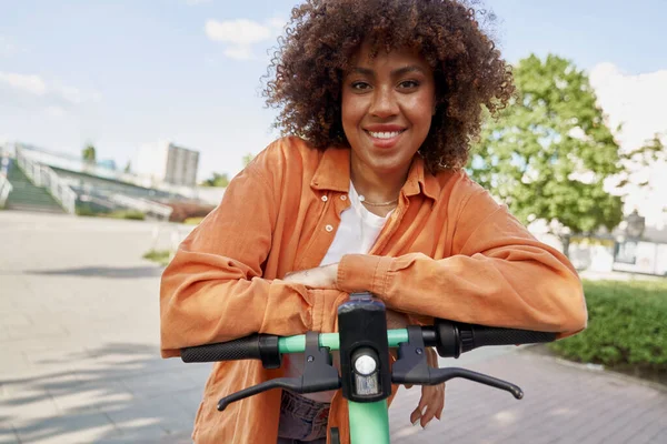 電動スクーターに乗る黒人女性のフロントビュー — ストック写真