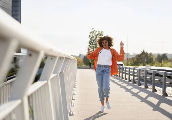 ヘッドフォンを着て橋の上で踊る黒人女性のワイドショット — ストック写真