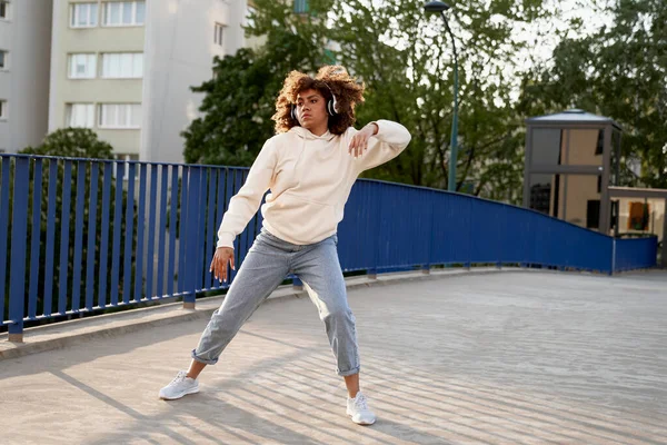 ヘッドフォンを着て橋の上で踊る黒人女性のワイドショット — ストック写真