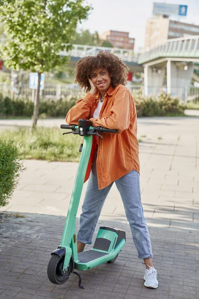 電動プッシュスクーターに乗る黒人女性の肖像画 — ストック写真