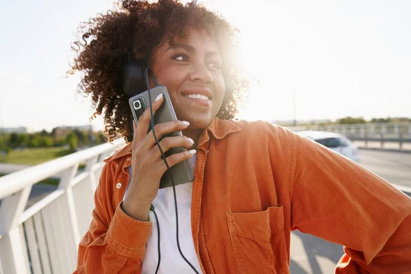 ヘッドフォンをして橋の上を歩く黒人女性 — ストック写真