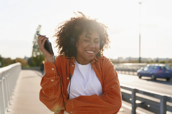 陽気黒の女性はヘッドフォンを着用し 橋の上で踊る — ストック写真