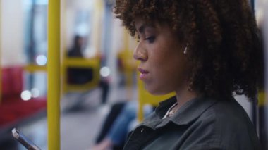 Yeraltından geçen ve cep telefonuna göz atan genç afro kadının yan görüntüsü. 8K 'da kırmızı helyum kamerayla çekildi.. 