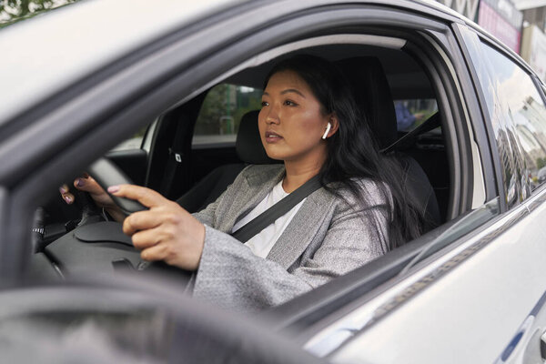 Chinese woman using earphones while driving a car