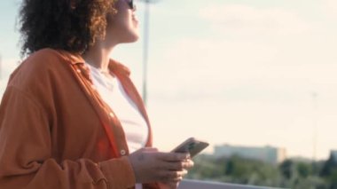 Siyah bir kadın köprüden geçiyor ve cep telefonuna bakıyor. 8K 'da kırmızı helyum kamerayla çekildi.. 