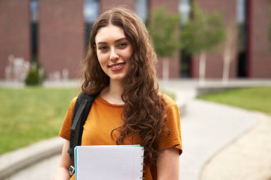 Portrait of caucasian university student standing outside the university campus  clipart