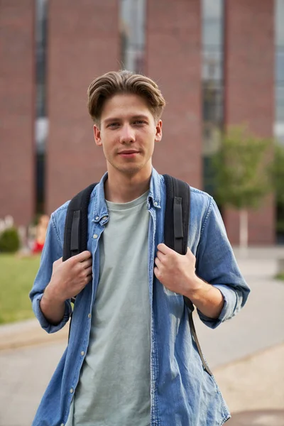 Portrait of male university student standing outside the university campus