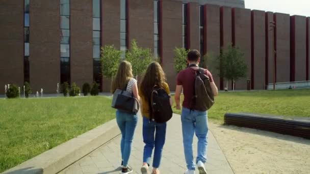 大学のキャンパスを歩く3人の白人学生のバックビュー 8Kでレッドヘリウムカメラで撮影 — ストック動画
