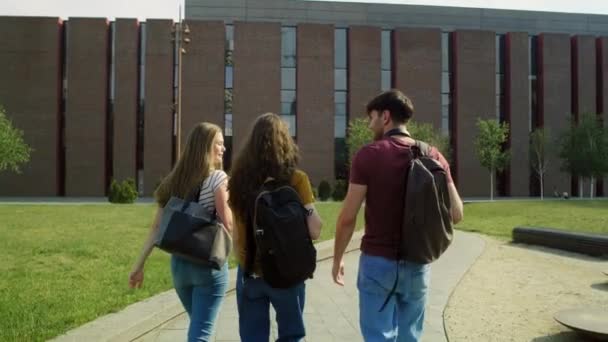 Achteraanzicht Van Drie Kaukasische Studenten Die Door Universiteitscampus Lopen Opgenomen — Stockvideo