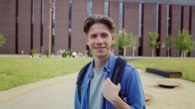 Üniversite kampüsünün dışında duran erkek üniversite öğrencisinin portresi. 8K 'da kırmızı helyum kamerayla çekildi.. 