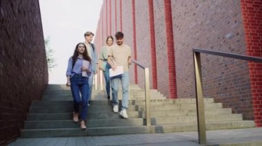 Üniversite kampüsünde merdivenlerden inen üç beyaz öğrenci. 8K 'da kırmızı helyum kamerayla çekildi..  
