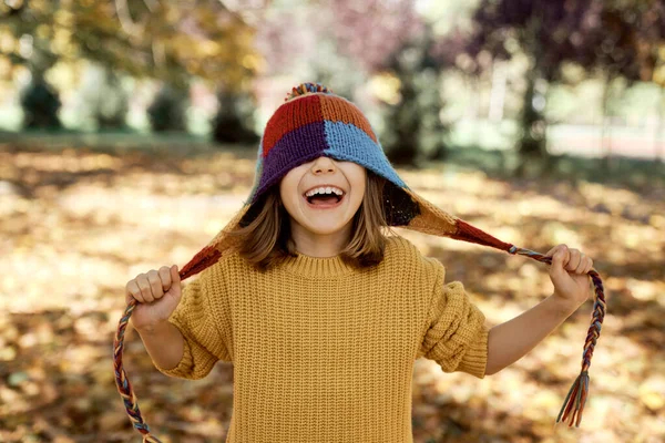 白人の女の子は森の中に立って面白いカラフルな帽子をかぶって — ストック写真