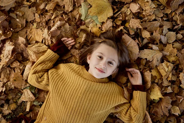 白人の女の子は葉で地面に横たわっています — ストック写真