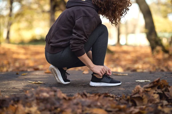公園でジョギングする前に靴を結ぶスポーツ服の女性 — ストック写真