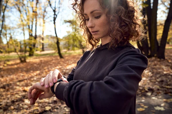 Caucasian woman using watch during doing sport in the park