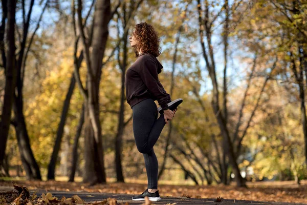 在公园慢跑前 一大片红头发的女人伸展着身体 — 图库照片