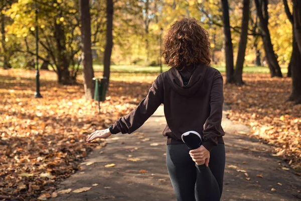 公園でジョギング前に伸びる赤い頭の女性のリアビュー — ストック写真