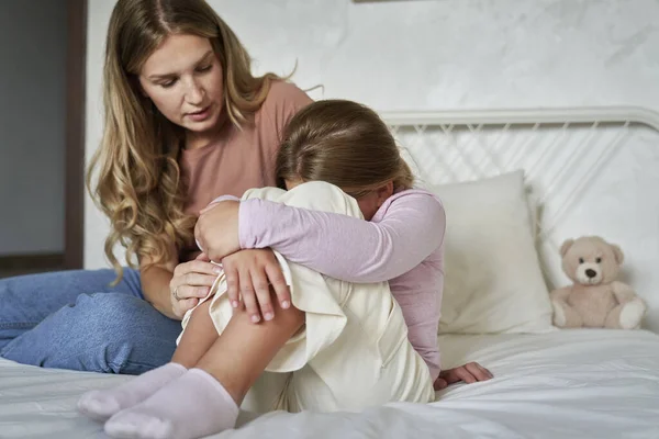 Mother Consoling Elementary Age Girl Sitting Bed Head Hidden Legs — Stock Photo, Image