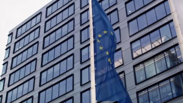 欧州連合の旗が建物の背景を振っている 8KでRedヘリウムカメラで撮影する — ストック動画