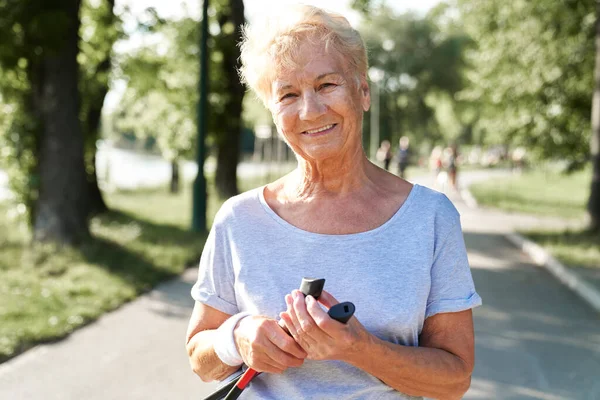 Portrait of senior woman holding nordic walking  sticks in the park