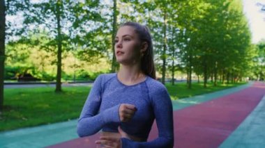 Genç beyaz kadın parkta koşmadan önce geriniyor. 8K 'da kırmızı helyum kamerayla çekildi..  