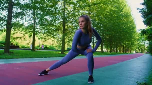 公園でジョギングする前に伸びている若い白人女性のワイドショット 8KでRedヘリウムカメラで撮影する — ストック動画
